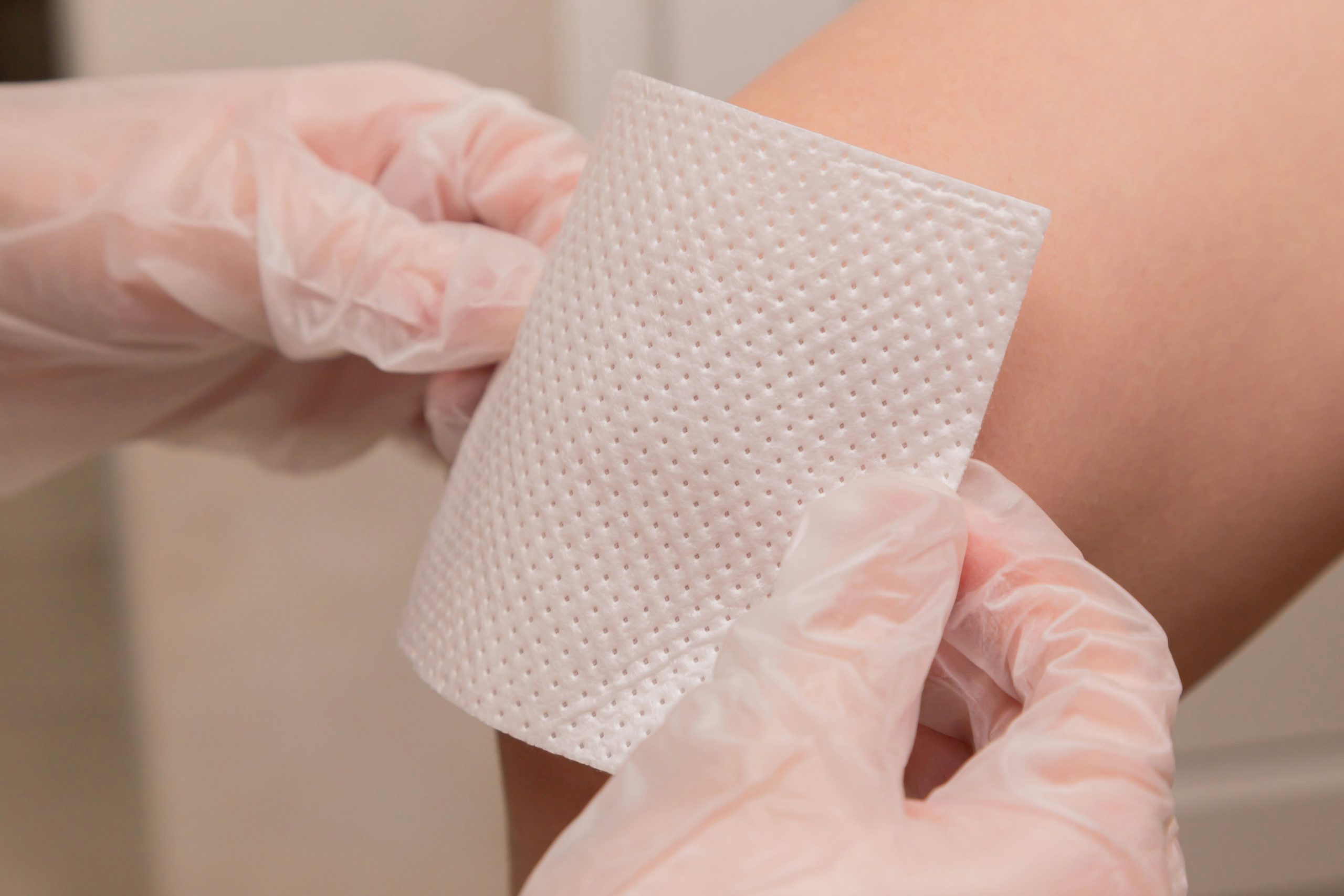 hands applying gauze to a knee, symbolising healing and recovery